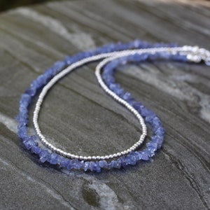 Peut inclure: Un collier délicat en chaîne argentée avec une couche de perles de pierres précieuses bleues. Le collier est composé de petites perles de forme irrégulière.