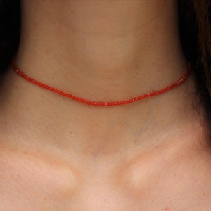 Puede incluir: Un delicado collar de cuentas rojas que se lleva en el cuello.