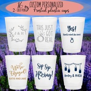 May include: Six 16 ounce white frosted plastic cups with different engagement-themed designs. The designs include "J & H" with a floral wreath, "This Just Got Real" with a ring, "Yes! That's what she said" with a ring, "We're Engaged! Katie and Jake", "Sip Sip. Hooray!" with a ring, and "Hailey & Mitch" with mason jars hanging from a string.