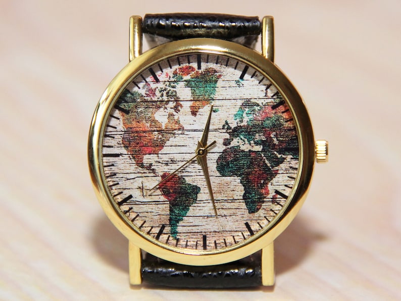 May include: A gold-tone wristwatch with a black leather band. The watch face features a world map design with a woodgrain texture and colorful accents.