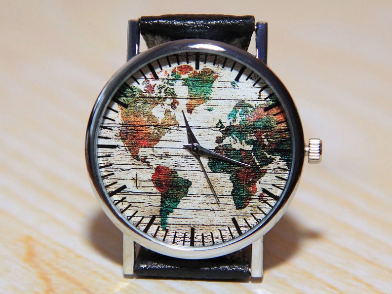 May include: A silver wristwatch with a black leather band. The watch face features a colorful world map design on a woodgrain background.