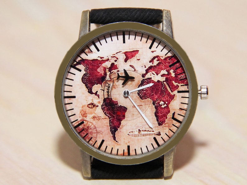 May include: A brown leather wristwatch with a round face featuring a vintage world map design. The watch face has black hour and minute hands and a black airplane icon in the centre.