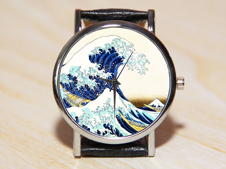 May include: A silver wristwatch with a black leather band features a colorful print of "The Great Wave off Kanagawa" by Katsushika Hokusai.