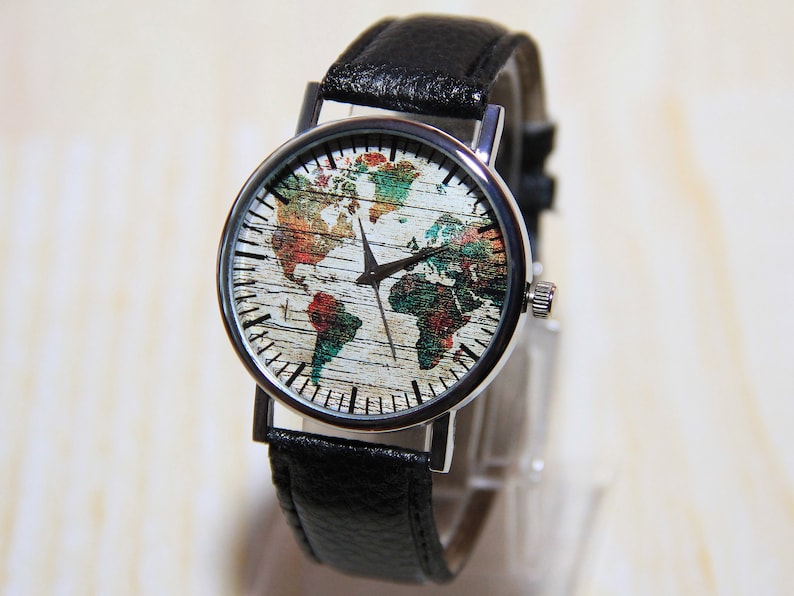 May include: A silver watch with a black leather band. The watch face features a colorful world map design.