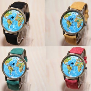 May include: Four wristwatches with different coloured bands. Each watch has a round face with a world map design and a small airplane graphic. The watch bands are black, yellow, green, and red.