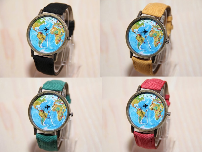 May include: Four wristwatches with different coloured bands. Each watch has a round face with a world map design and a small airplane graphic. The watch bands are black, yellow, green, and red.