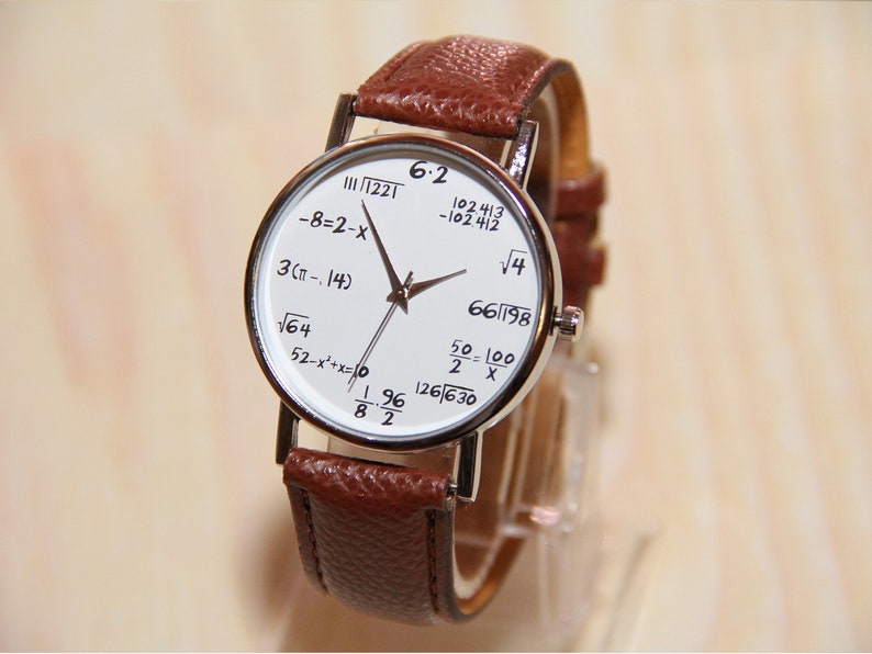 May include: A white wristwatch with a brown leather band. The watch face features various mathematical equations, including 6.2, 102.413, -102412, &radic;4, 66/198, 50/2=100/x, 3(&pi;-.14), &radic;64, 52-x&sup2;+x=10, 126/630, 1.96/82, and 1221.