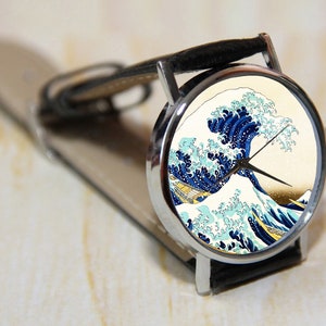 May include: A silver wristwatch with a black leather band features a colorful print of "The Great Wave off Kanagawa" by Katsushika Hokusai.