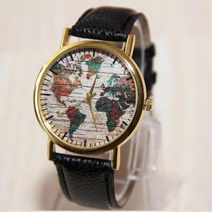 May include: A gold-tone wristwatch with a black leather band. The watch face features a colorful world map design.