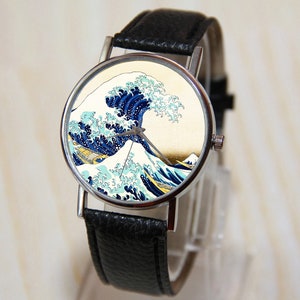 May include: A silver wristwatch with a black leather band. The watch face features a colorful image of "The Great Wave off Kanagawa" by Katsushika Hokusai.