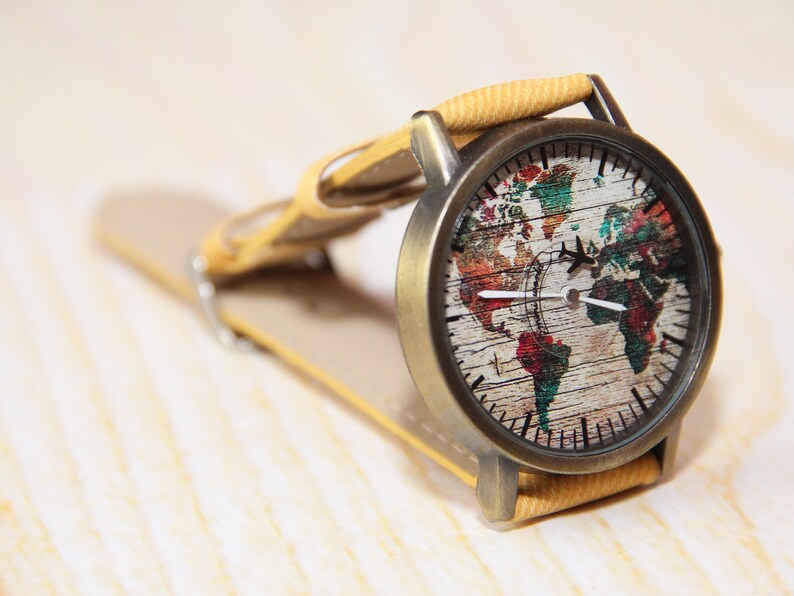 May include: A vintage-style wristwatch with a brown leather band and a round face featuring a colorful world map design.