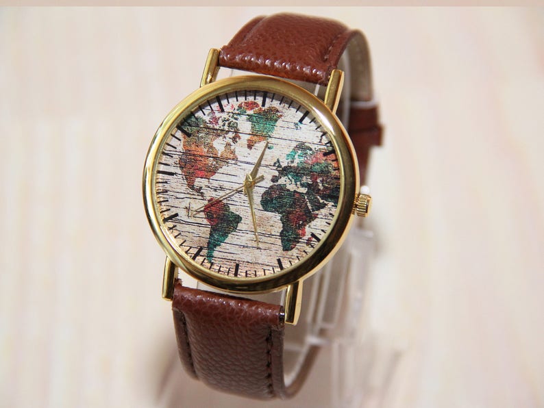 May include: A brown leather wristwatch with a gold-tone case. The watch face features a colorful world map design.