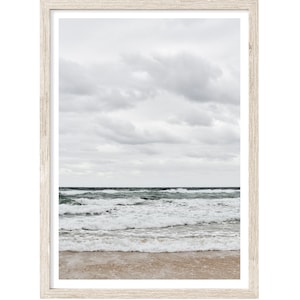 May include: A framed photograph of a beach scene with white foamy waves crashing on the shore. The sky is overcast with gray clouds.