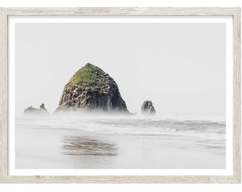 May include: A misty seascape with a large, rocky island covered in green vegetation in the foreground. The island is surrounded by a calm, white-capped ocean.