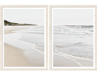 May include: Two framed prints of a beach scene with white sand, blue water, and waves crashing on the shore. The left print shows a distant shoreline with green vegetation, while the right print focuses on the waves.