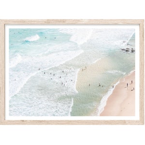 May include: An aerial view of a beach with turquoise water and white sand. People are swimming and wading in the water, while others are walking along the shore.