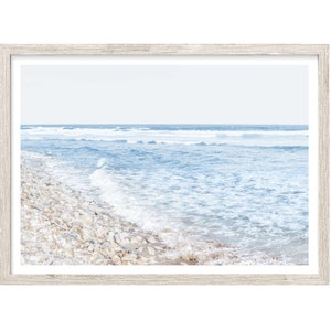 May include: A framed photograph of a beach scene with white rocks and blue ocean waves crashing on the shore.