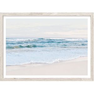 May include: A framed photograph of a beach scene with white sand, blue water, and white foamy waves.