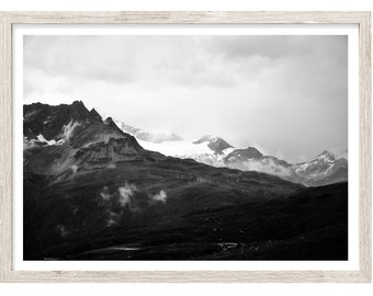 May include: A black and white photograph of a mountain range with snow-capped peaks and clouds in the sky.