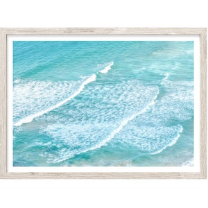 May include: An aerial view of turquoise ocean water with white foamy waves crashing in rows.