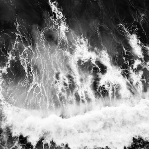 Puede incluir: Fotograf&iacute;a a&eacute;rea en blanco y negro de una gran ola rompiendo en el oc&eacute;ano. La ola se rompe en espuma blanca y el agua es oscura y turbulenta.