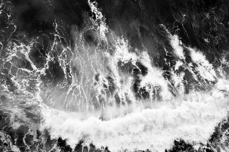 Puede incluir: Fotograf&iacute;a a&eacute;rea en blanco y negro de una gran ola rompiendo en el oc&eacute;ano. La ola se rompe en espuma blanca y el agua es oscura y turbulenta.