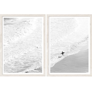 May include: A black and white photo split into two frames. The left frame shows a close-up of foamy ocean waves crashing on the shore. The right frame shows a lone surfer walking on the beach with a surfboard under their arm.
