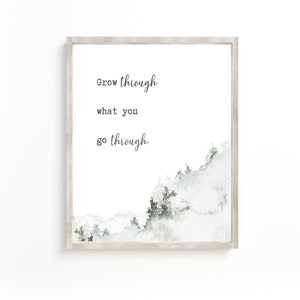 May include: A framed print with a watercolour background of a mountain range in shades of green and white. The text "Grow through what you go through." is printed in black on a white background.
