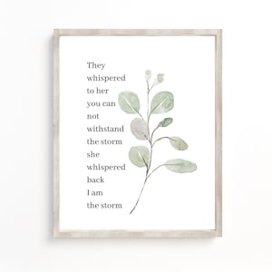 Könnte beinhalten: Ein gerahmter Druck mit einer Aquarellillustration eines grünen Eukalyptusastes und einem Gedicht, das lautet: "Sie flüsterten ihr zu, dass du dem Sturm nicht standhalten kannst, sie flüsterte zurück: Ich bin der Sturm."
