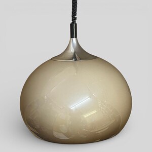 May include: Cream-coloured, spherical pendant light with a silver-coloured metal base and a black cord. The light fixture has a glossy finish and a rounded shape, suitable for interior lighting.