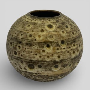 May include: A spherical ceramic vase with a textured surface. The vase is predominantly tan and brown, featuring dark brown circular indentations. The opening at the top is dark brown. The vase has a rounded shape, suitable for home decor.