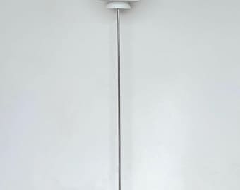 May include: A white floor lamp with a chrome base and three tiered white lampshades. The lamp has a white cord and a white switch.