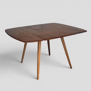 May include: A dark brown wooden dining table featuring a rectangular top with rounded edges and a visible wood grain pattern. The table is supported by four light brown tapered wooden legs that angle outward from the centre of the base.