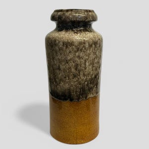 May include: A brown and beige ceramic vase with a brown glaze. The vase has a wide mouth and a narrow base.