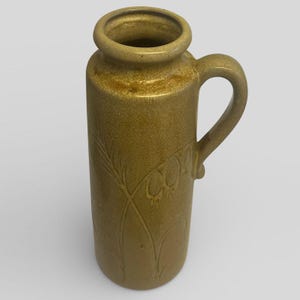 May include: An olive-green ceramic jug with a handle and a wide opening. The jug features an embossed floral design. The handle is curved and attached to the side. The jug is approximately 20 cm tall.