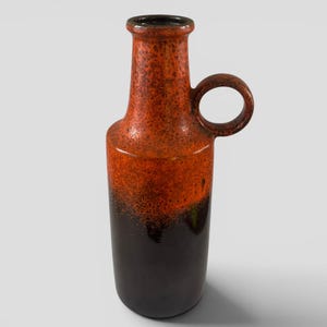 May include: A tall, ceramic vase with a bottle-like shape. The upper portion is a speckled orange, transitioning to a dark brown base. It features a rounded handle and a narrow neck. The vase is approximately 25 cm tall.