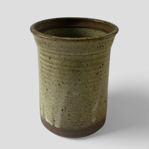 May include: A brown and white ceramic vase with a speckled glaze. The vase has a rounded bottom and a wide opening.