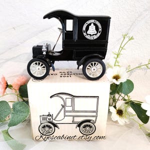 May include: A black 1908 delivery car model with a bell logo on the side. The model is on a white box with the text "1908 DELIVERY CAR" and "AMERICAN TELEPHONE & TELEGRAPH" printed on it.