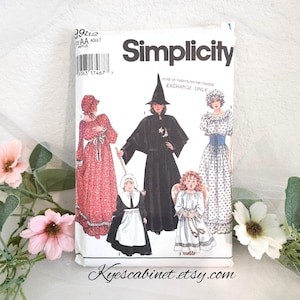 May include: A Simplicity sewing pattern featuring illustrations of various costumes, including a witch, angel, and pilgrim. The pattern packet is white with black text and images. The Etsy shop name "Kyescabinet.etsy.com" is printed at the bottom.