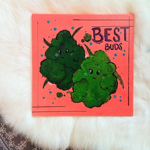 May include: Square canvas art featuring two cartoon green buds with smiling faces, set against a coral background. The words "BEST BUDS" are written in purple. Blue dots and black lines add detail to the artwork.