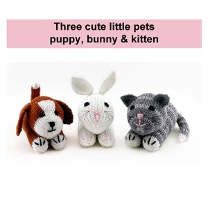 May include: Three knitted stuffed animals: a brown and white puppy, a white bunny, and a gray and white kitten. The animals are all lying down and looking at the camera.