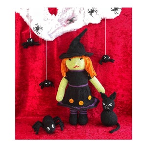 May include: A handmade Halloween-themed knitted witch doll with orange hair, a black dress, and a pointed hat. The scene includes a black cat, spiders, and a spider web against a red backdrop. The witch doll has green skin and is decorated with pumpkin appliques.