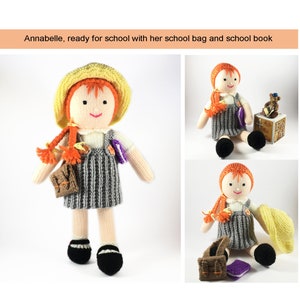 May include: A knitted doll with red hair, wearing a yellow hat, a grey and white striped dress, and carrying a brown bag and a purple book. The doll is ready for school.