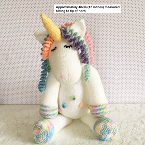 May include: A white knitted unicorn doll with a yellow horn, rainbow mane, and multi-colored accents. The doll is approximately 17 inches tall. It has closed eyes and colorful details on the feet and body.