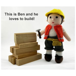 May include: A knitted toy wearing a yellow hard hat, orange vest, and brown pants holds a small hammer. The toy is standing next to a stack of wooden blocks. The text "This is Ben and he loves to build!" is written above the toy.