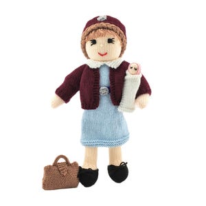 May include: Knitted doll wearing a burgundy cardigan, blue dress, and a brown hat. The doll is holding a smaller knitted doll in its arms. The doll is carrying a brown handbag.