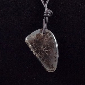 May include: A black leather cord necklace with a dark gray, irregularly shaped stone pendant.