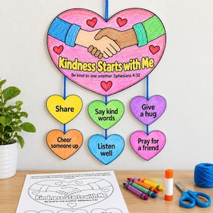 May include: A hanging mobile craft featuring a large pink heart with a handshake illustration and the text Kindness Starts with Me. Below, six smaller coloured hearts hang by blue yarn, each printed with positive actions like Share and Listen well.