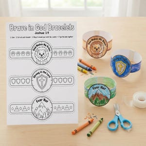 May include: A craft kit featuring a printed sheet titled Brave in God Bracelets with three designs: a lion, a shield with a cross, and mountains. Three finished paper bracelets colored with crayons are displayed alongside scissors and tape.