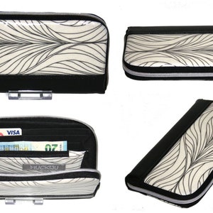 Op de afbeelding: Een zwarte en cr&egrave;mekleurige portemonnee met een vloeiend, bladvormig patroon. De portemonnee heeft een zwarte rits en afwerking en wordt in meerdere weergaven getoond, waaronder een open weergave met kaarten en contant geld.